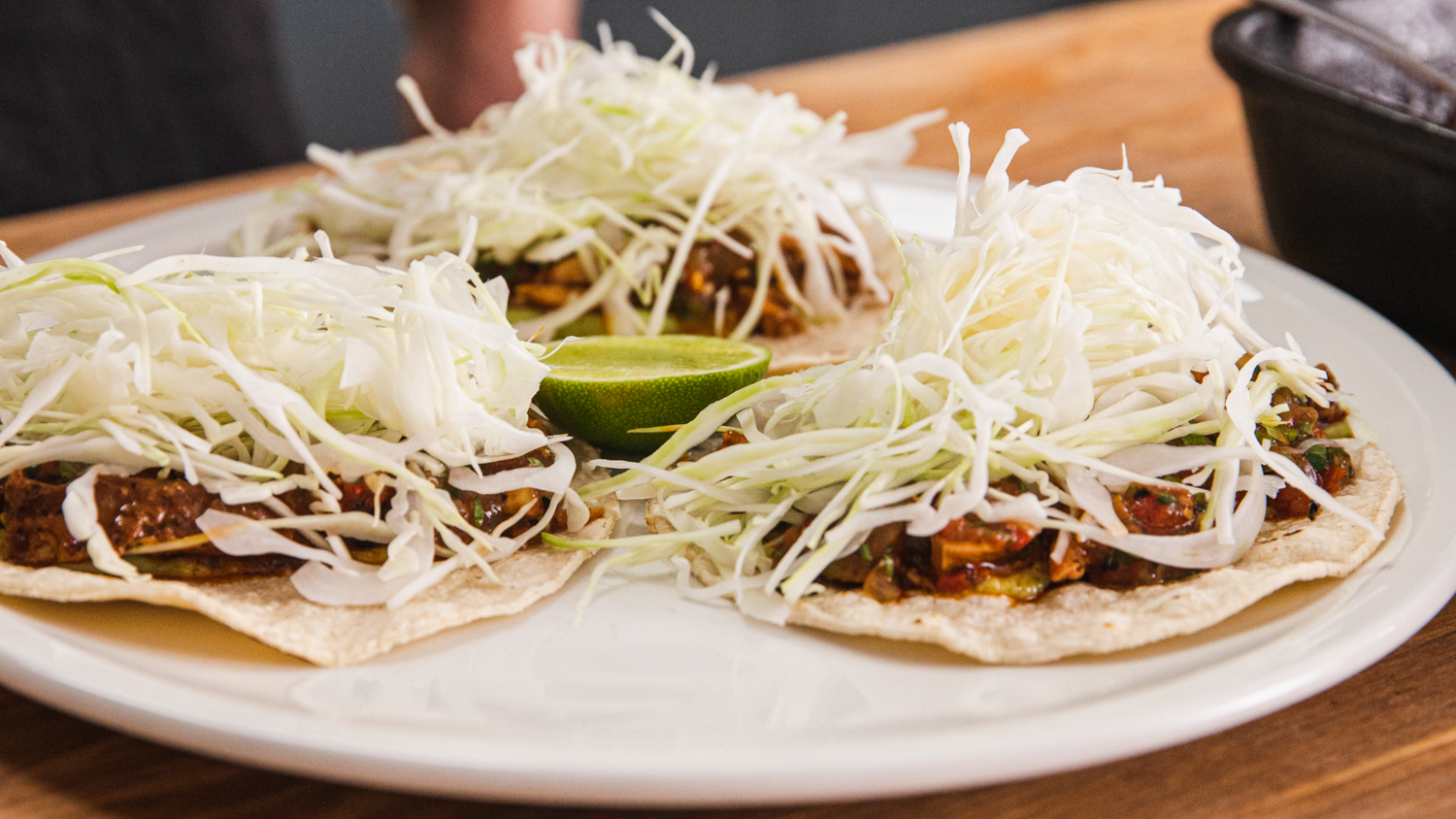 Three chicken tacos arranged on a plate with half a lime in the middle. recipe poster image