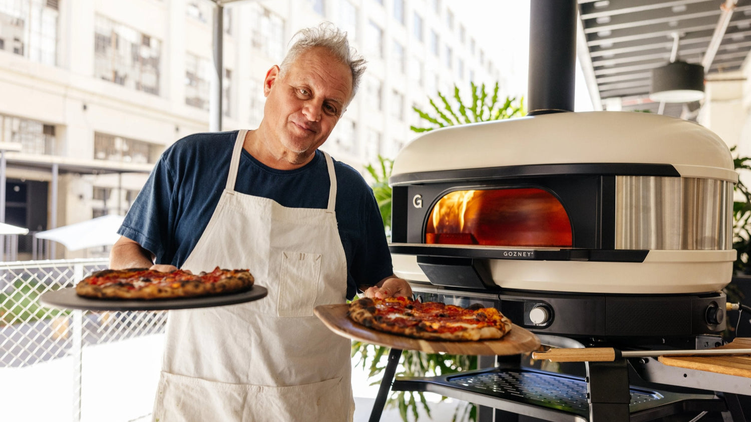 Chris Bianco holding two pizzas in front of Dome (Second Generation)
