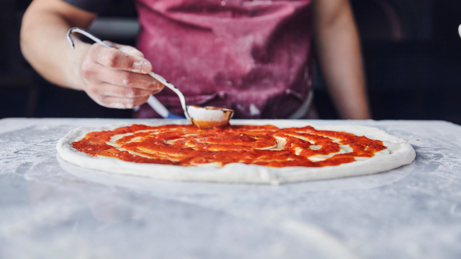 Marinara Sauce spread over pizza dough