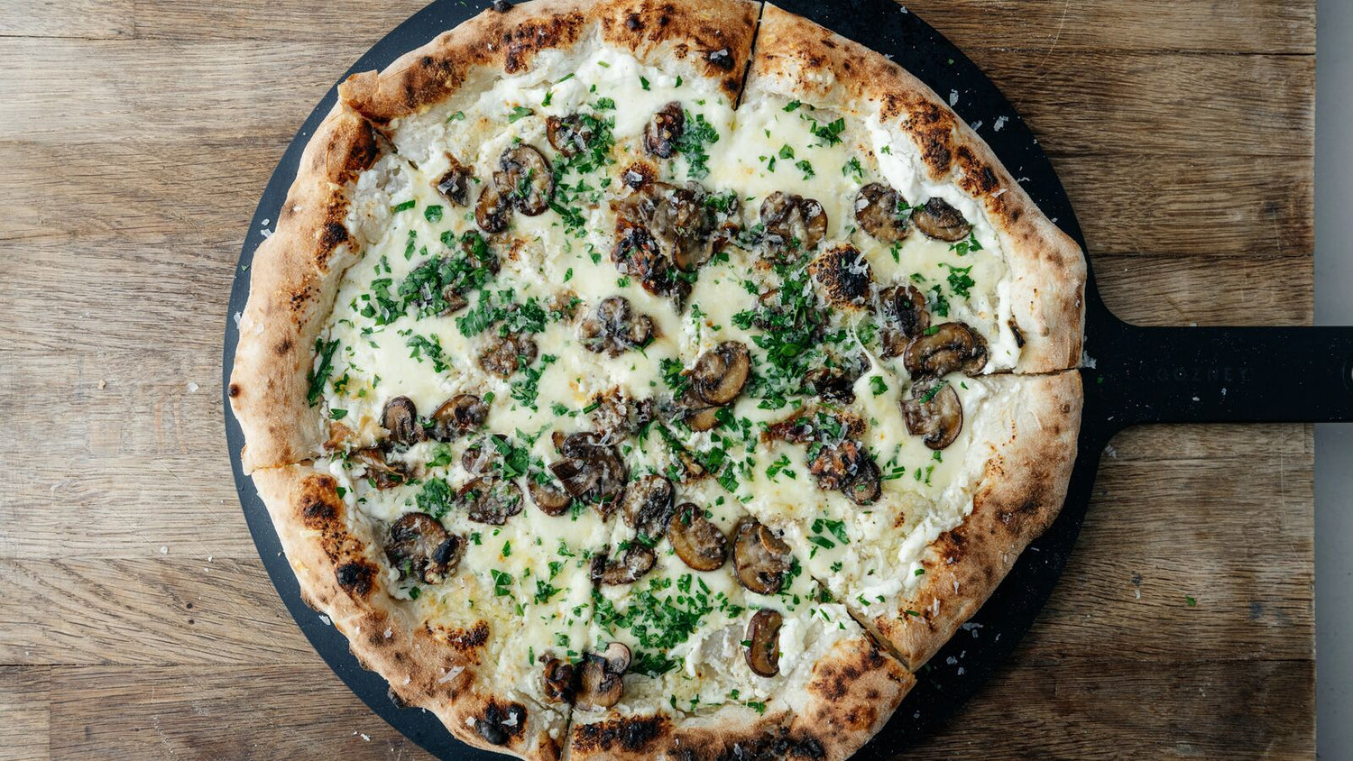 Roasted Mushroom Pizza Bianca on a pizza server on a cutting board